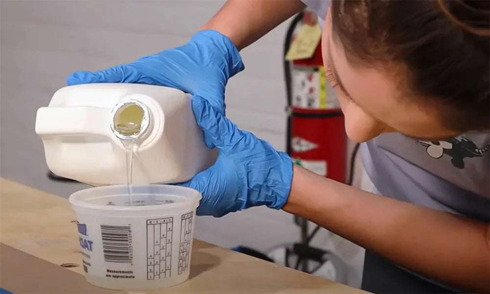 person pouring epoxy in to a mixing cup