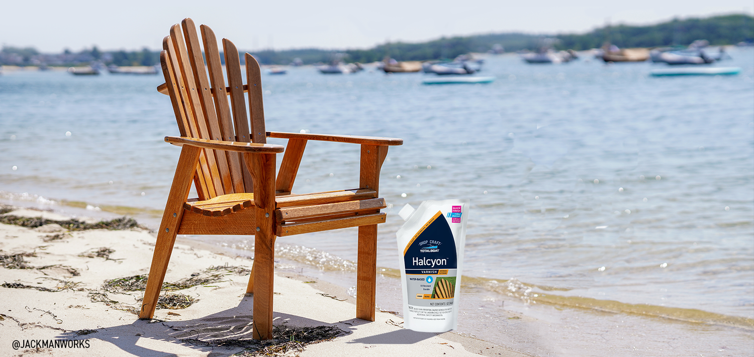 TotalBoat Halcyon Shown with Varnished Adirondack Chair on Beach in Background