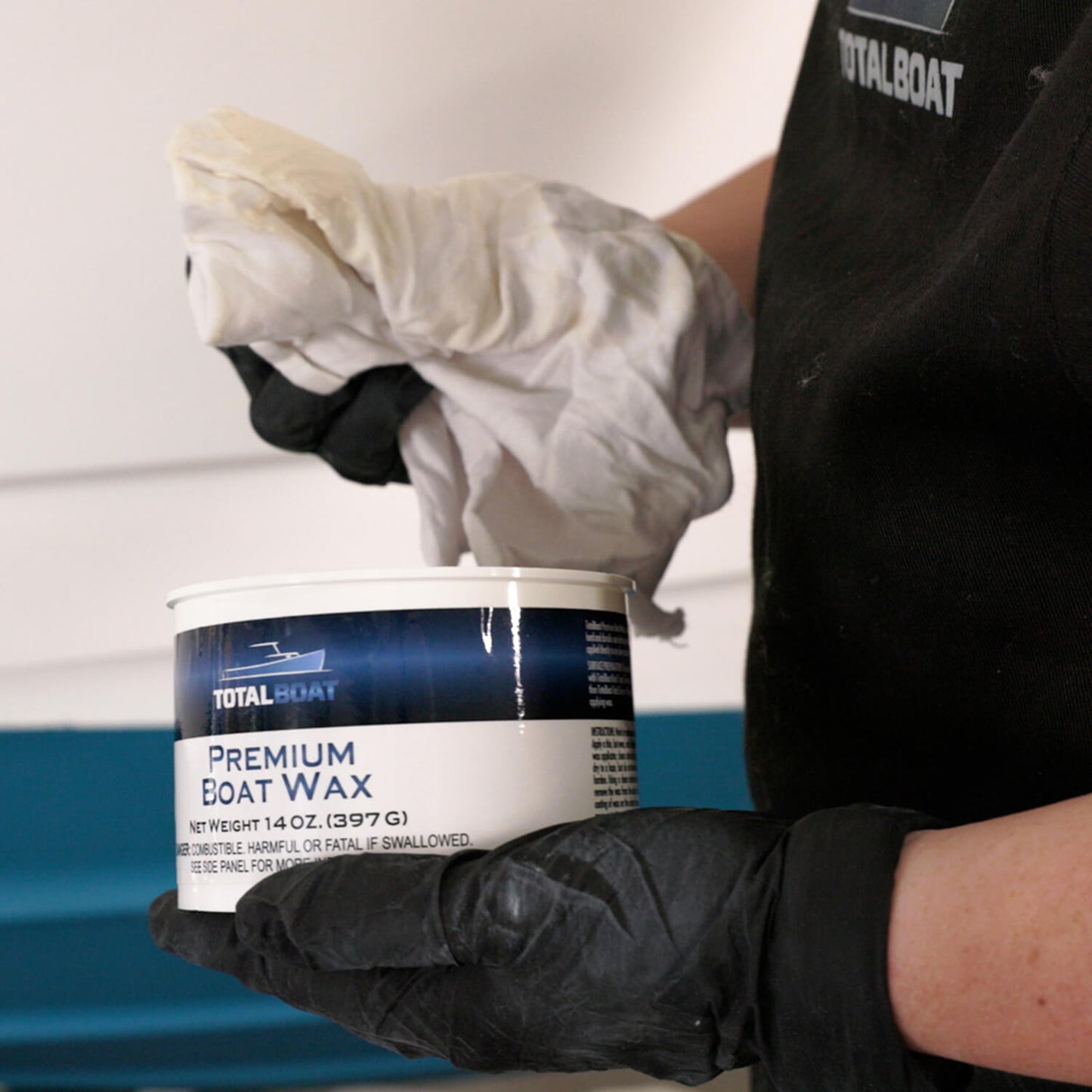 TotalBoat Premium Boat Wax being applied to a boat with a rag