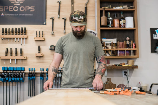 Jason Hibbs measuring a hardwood board in his woodworking shop before milling