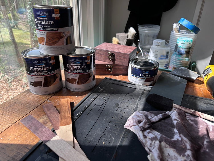wood stain cans with swatches on a desk by window