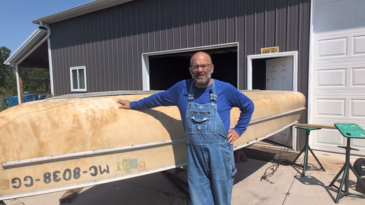 Matt in overalls leaning up against his boat