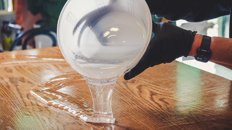 plastic bucket pouring epoxy on to a wood table top