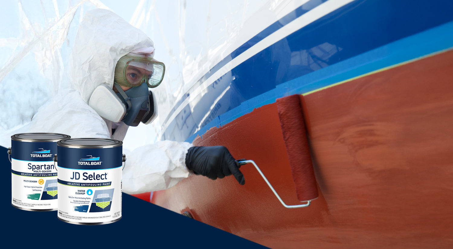A do-it-yourself boater maintaining his sailboat with the application of TotalBoat Antifouling Paint before putting the boat in for the season. TotalBoat JD Select Ablative Antifouling Bottom Paint, TotalBoat Spartan Ablative Antifouling Paint and Underdog Ablative Antifouling bottom paint cans are showcased in the frame, in front of the photo.
