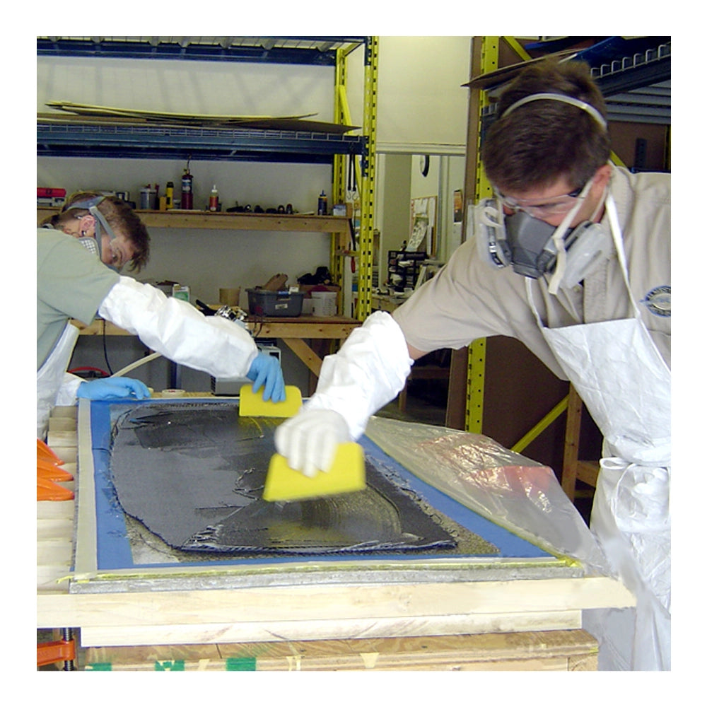 Two men spreading epoxy resin on unidirectional carbon fiber