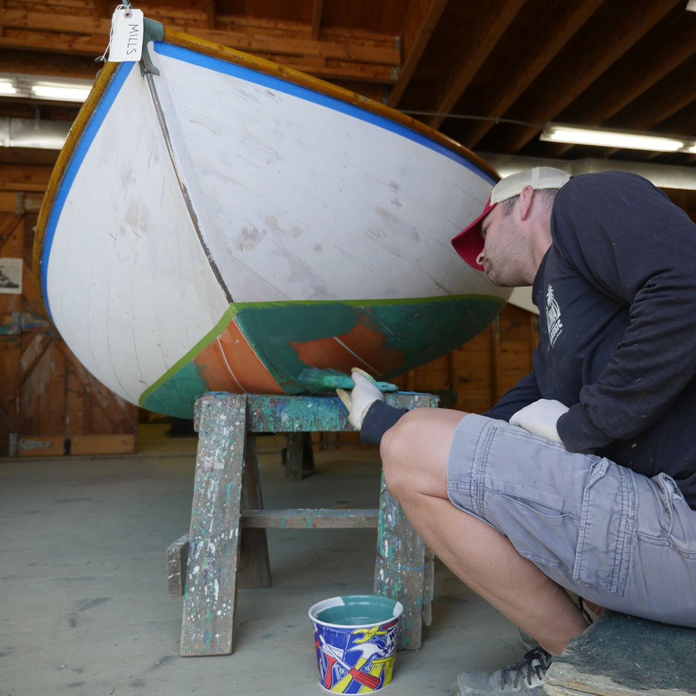 TotalBoat Spartan Multi-Season Antifouling Paint Green being applied on a wooden boat with a brush