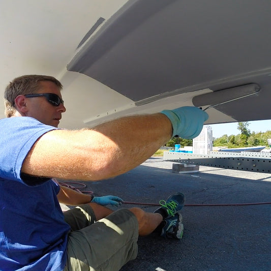 TotalBoat TotalProtect Epoxy Barrier Coat Primer gray being rolled on the bottom of a boat